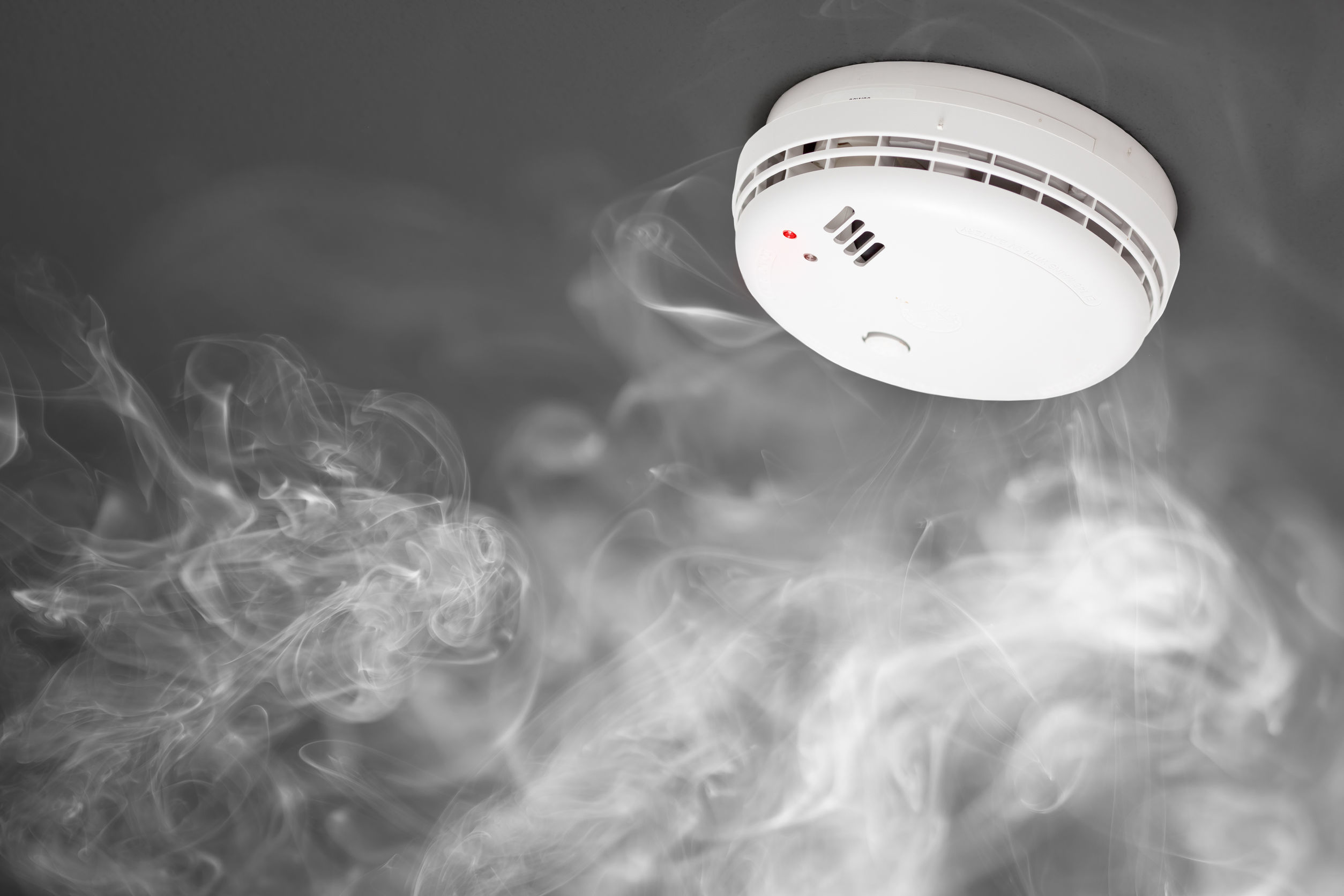 Rauchmelder an der Decke mit umgebendem Rauch, Bestandteil eines Brandmeldesystems von Limburger Sicherheitstechnik, einem VdS-zertifizierten Sicherheitsanbieter.