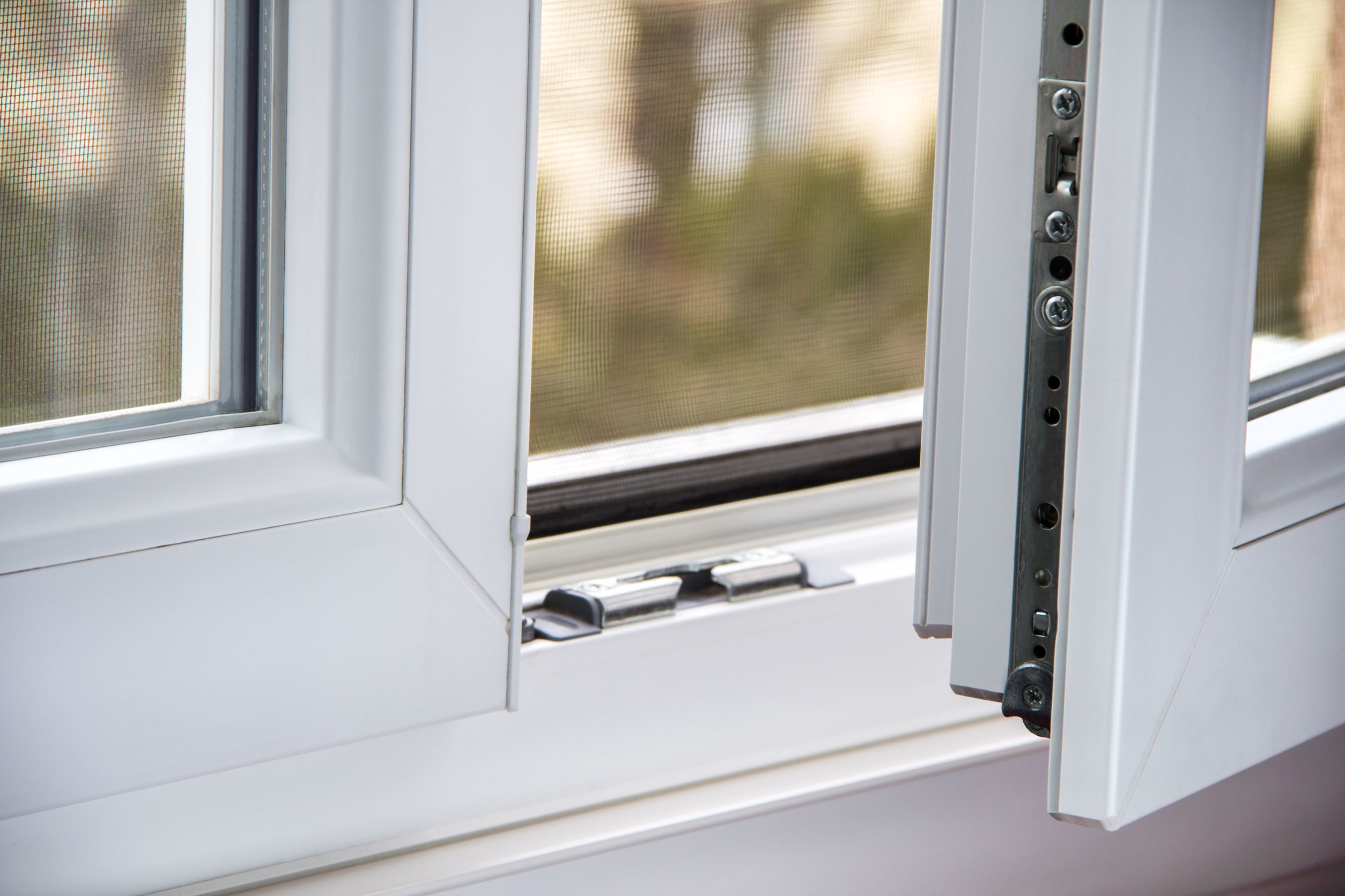 Close-up of a white Sicherheitsfenster (security window) showing its frame, screen, and security hardware, highlighting the robust design for burglary protection.